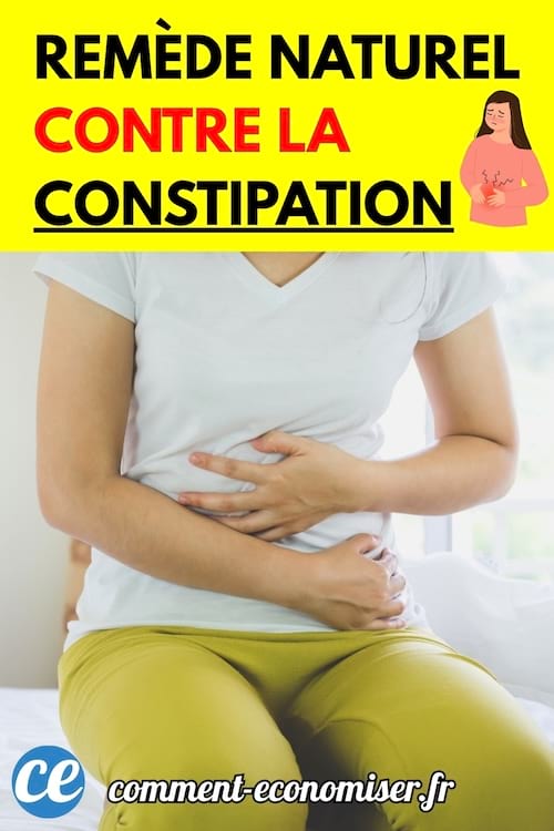 Femme assise sur un lit tenant son ventre avec les deux mains.