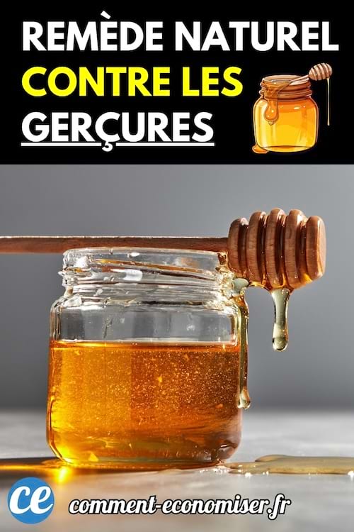 Pot de miel et cuillère en bois dégoulinante sur fond gris.