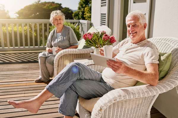 Un couple de retraités profite du soleil sur une terrasse.