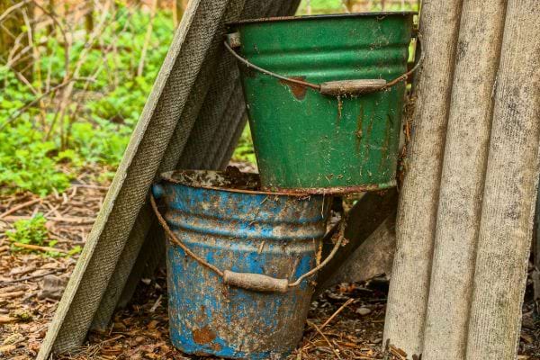 Seaux rouillés posés contre une planche.