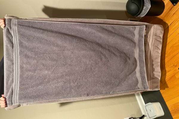 Grande serviette violette tenue à deux mains.