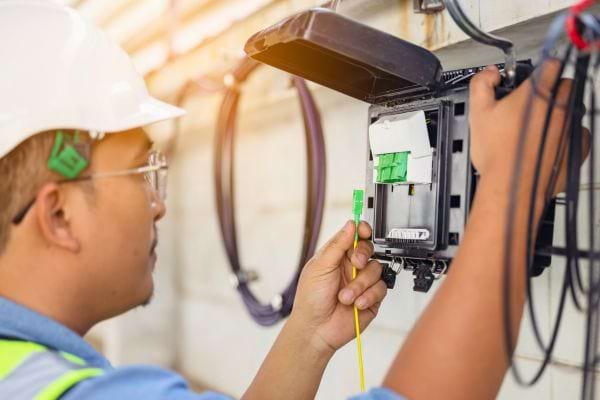 Technicien connectant un câble dans un boîtier mural.