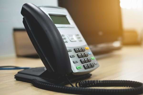 Téléphone fixe moderne sur un bureau lumineux.