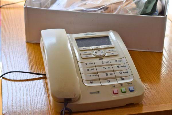 Téléphone beige ancien posé sur un bureau en bois.