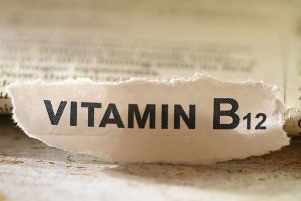 Gros plan sur le mot "vitamine B12" écrit sur un papier déchiré.