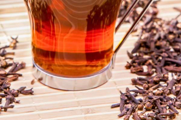 Tisane ambrée de girofle entourée d’épices sèches.