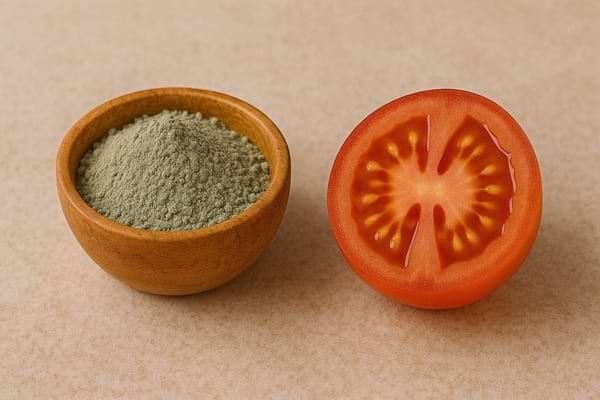 Une tomate est posée près d’argile verte en poudre.