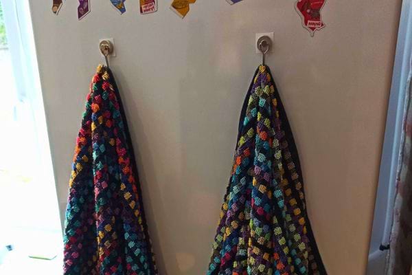 Torchons colorés suspendus à des crochets muraux.