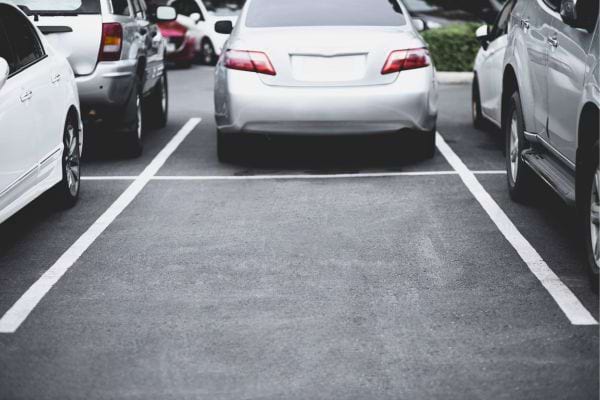 Une voiture grise bien stationnée au centre d’une place.