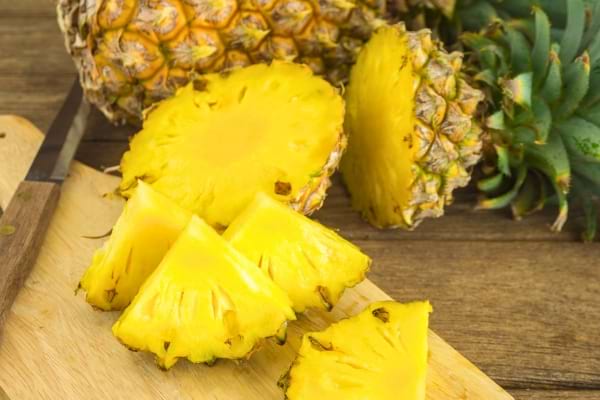De l’ananas frais coupé en tranches sur une planche.