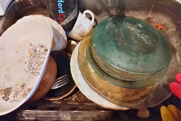 Assiettes et verres sales recouverts de résidus séchés.