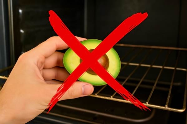 Main tenant un avocat devant un four avec une croix rouge dessus.