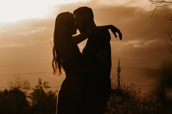 Silhouette d’un couple s’embrassant au crépuscule.