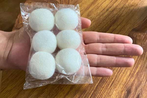 Une main tient un sachet de balles de lavage réutilisables.