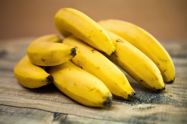 Une grappe de bananes mûres sur une table en bois.