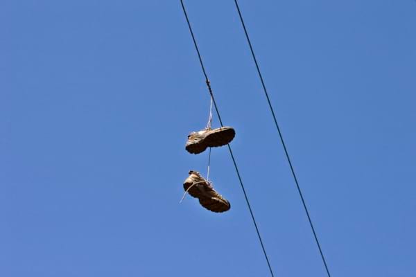 Des baskets suspendues à un fil électrique sur fond de ciel bleu.