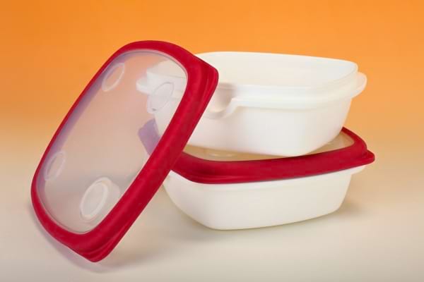 Deux boîtes hermétiques blanches avec couvercle rouge posées sur fond orange.