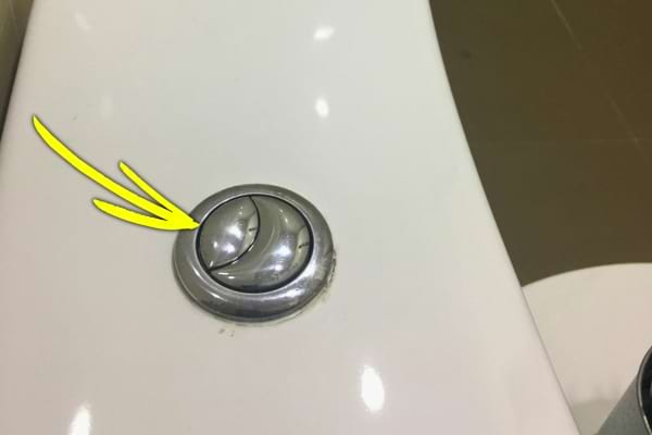 Trois flèches jaunes indiquent le grand bouton de la chasse d’eau.