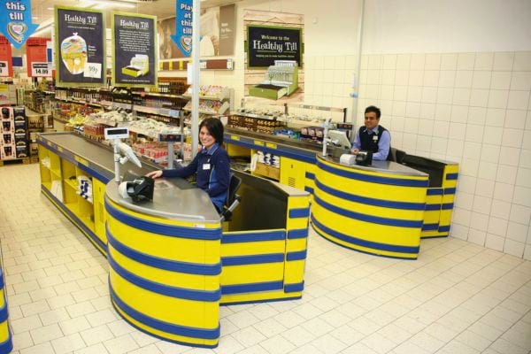 Deux caissiers Lidl derrière des caisses colorées.