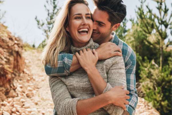 Un couple s’enlace et rit lors d’une balade.