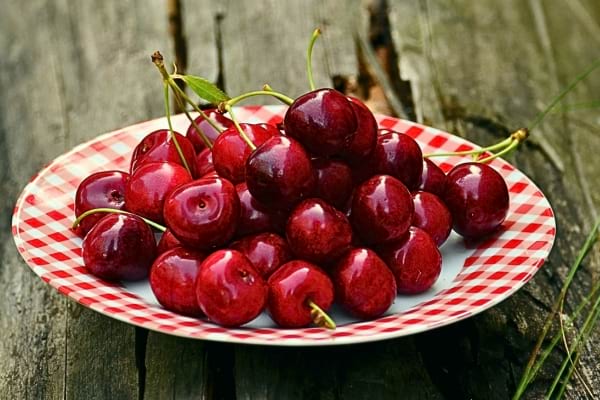 Une assiette remplie de cerises rouges brillantes.
