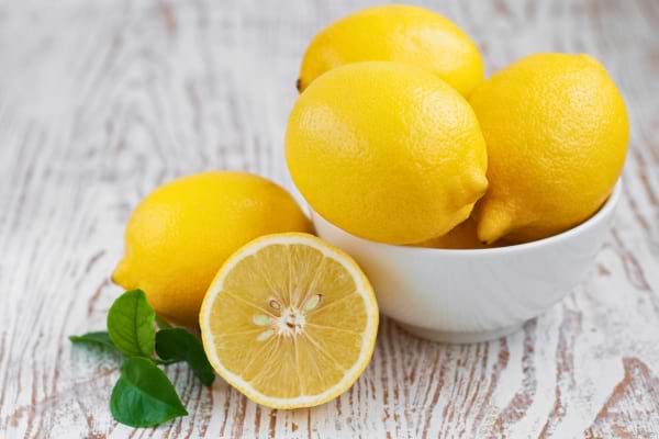 Des citrons frais posés dans un bol sur une table en bois.