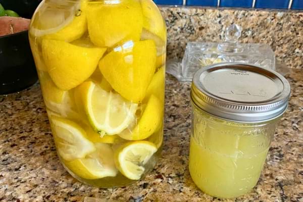 Un grand bocal de citrons trempés dans un liquide, à côté d’un petit pot. 