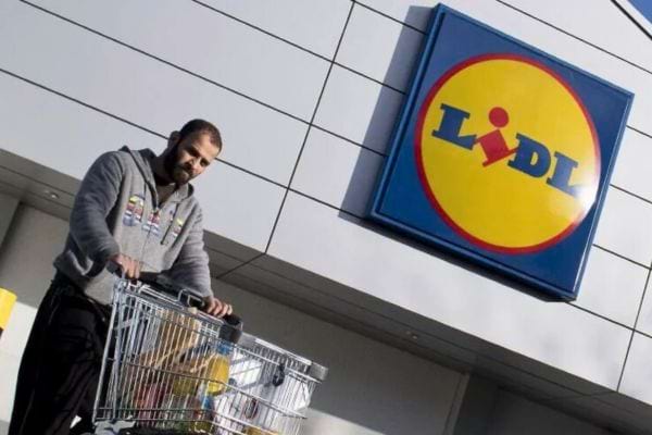 Un homme pousse un caddie plein devant Lidl.