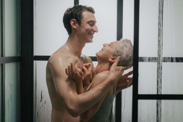 Un couple rit sous la douche en s’enlaçant tendrement.
