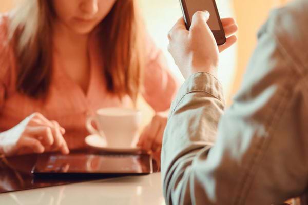 Un couple au café, absorbé par leurs écrans.