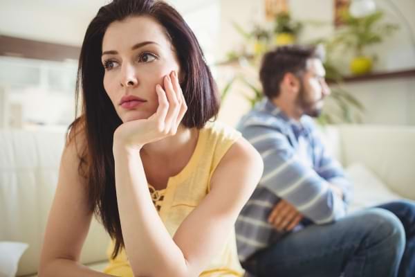 Een peinzende vrouw kijkt in de verte, haar rug naar haar partner toe.