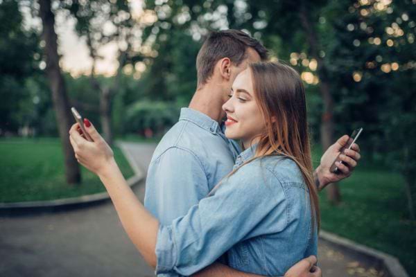 Un couple s’enlace sans quitter leurs écrans des yeux.