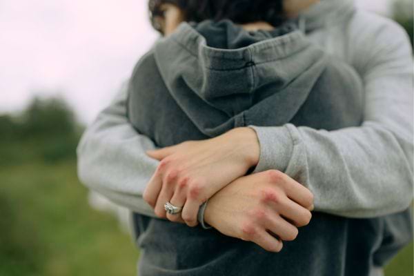 Deux personnes s’enlacent en silence, l’ambiance est froide.