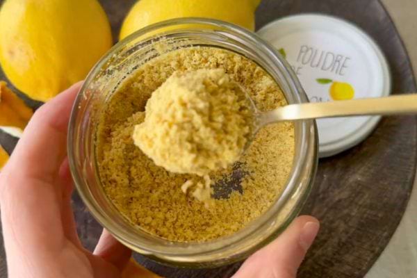 Cuillère pleine de poudre de citron au-dessus d’un bocal.