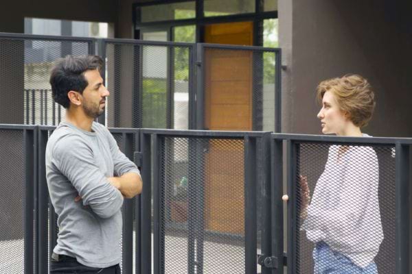 Un homme et une femme échangent sérieusement à travers une barrière.