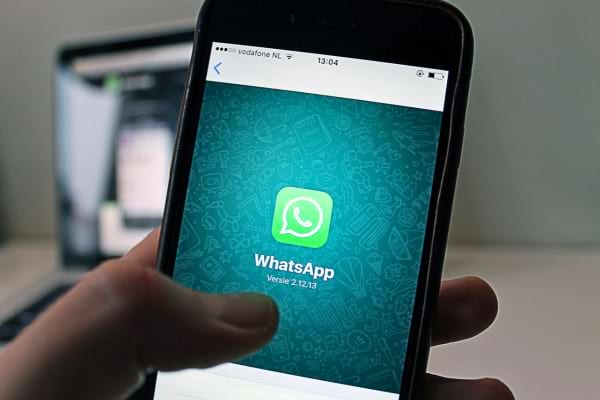 Un téléphone affiche l'écran d'accueil de l'application WhatsApp.