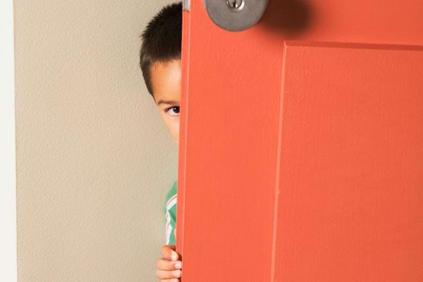 Enfant curieux regarde discrètement derrière la porte.