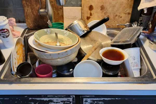 Vaisselle empilée et grasse avec bols, casseroles et tasses.