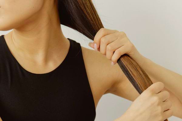 Femme tenant ses longs cheveux lisses.