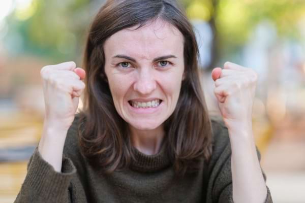 Une femme en colère serre les poings et les dents, peut-être irritée sans raison apparente.