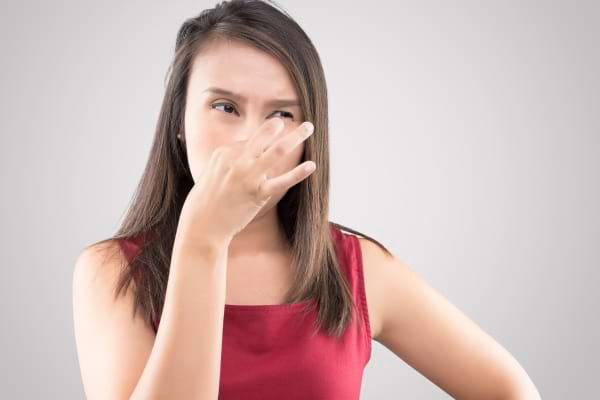 Une femme se pince le nez à cause d'une mauvaise odeur.