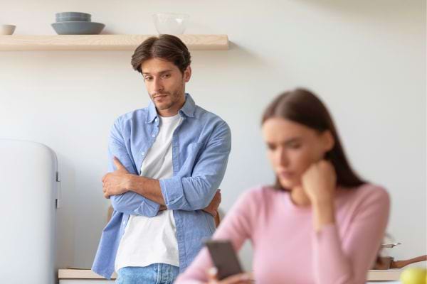 Un homme observe sa partenaire distraite par son téléphone.