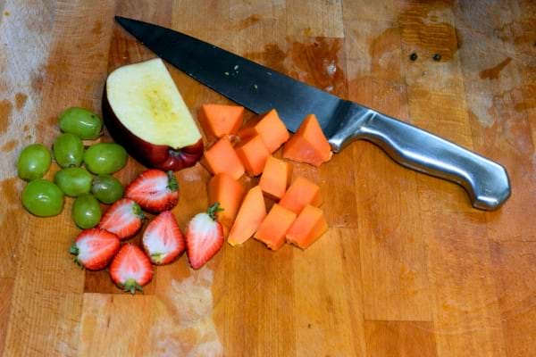 Des fruits frais coupés sur une planche en bois avec un couteau en acier.