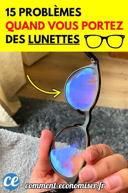 Une main tient une paire de lunettes avec des verres sales et des reflets bleus.