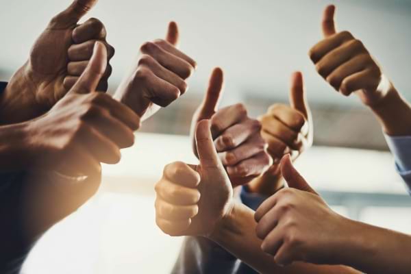 Plusieurs mains lèvent le pouce en signe d’approbation collective.