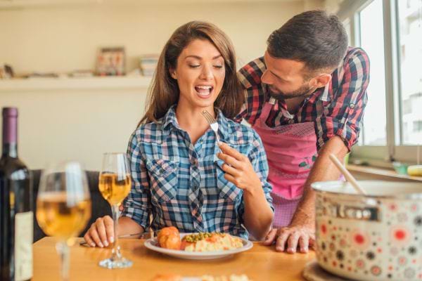 Un homme fait à manger pour sa compagne ravie.