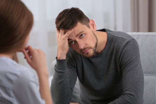 Un homme en pleine discussion, l’air préoccupé face à une femme.