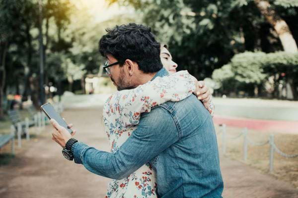 Homme en couple qui regarde son t&eacute;l&eacute;phone discr&egrave;tement.