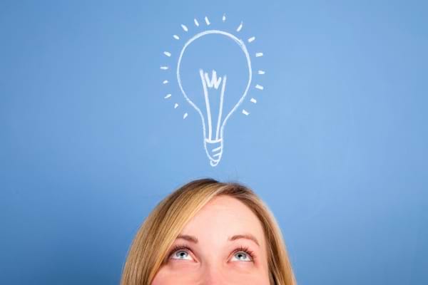 Une femme regarde en l’air avec une ampoule dessinée au-dessus de sa tête, symbolisant une idée.