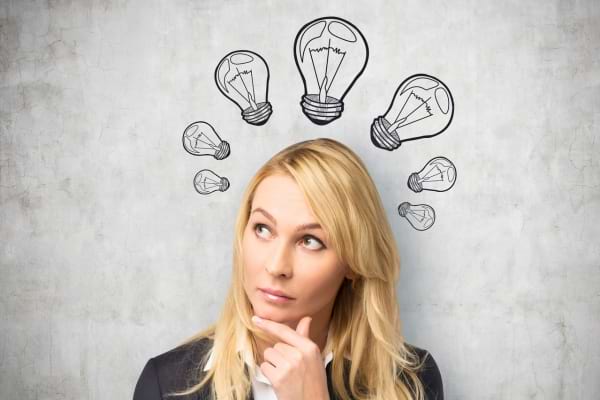Une femme pensive regarde vers le haut, entourée d’ampoules dessinées symbolisant des idées.